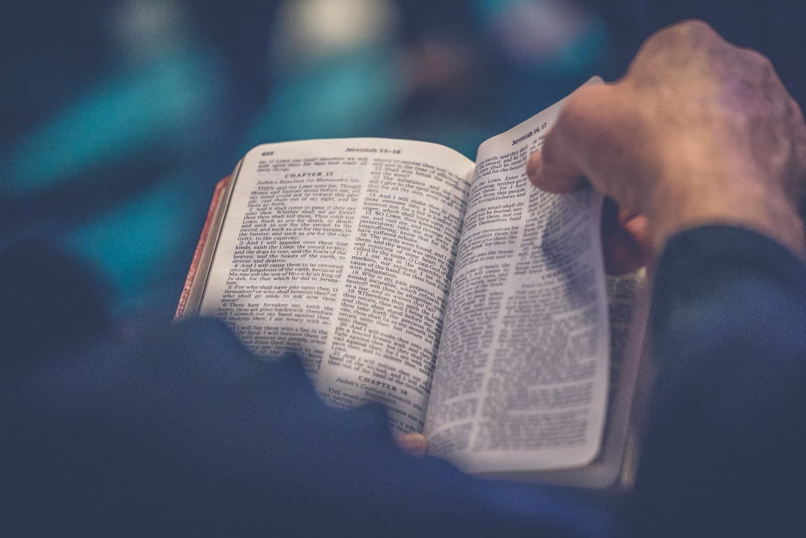 Hands quietly turning the pages of an open Bible